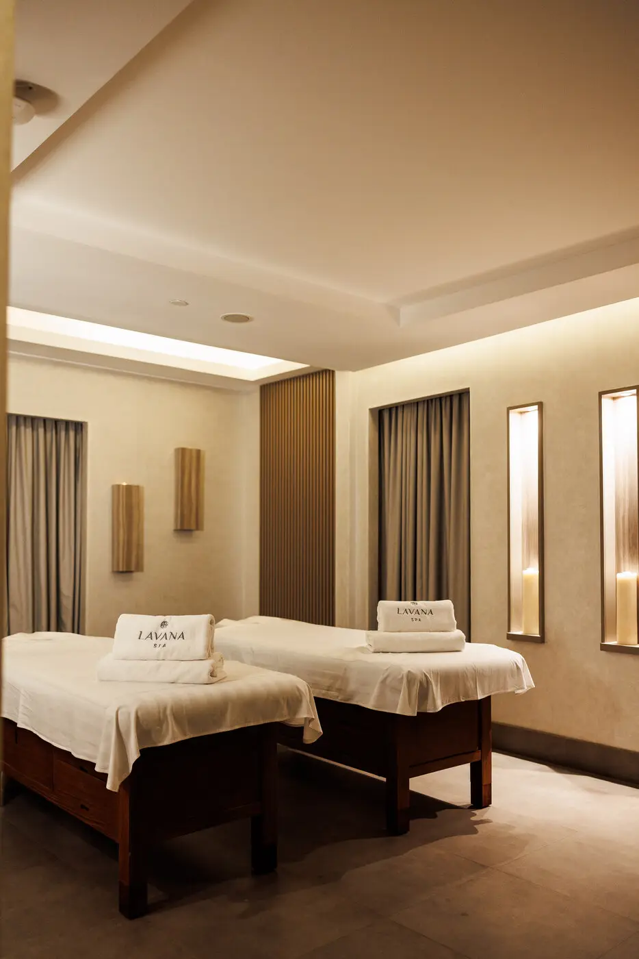 Couples treatment room at Lavana Spa DIFC: two beds made up with Lavana towels, candle niches along the wall