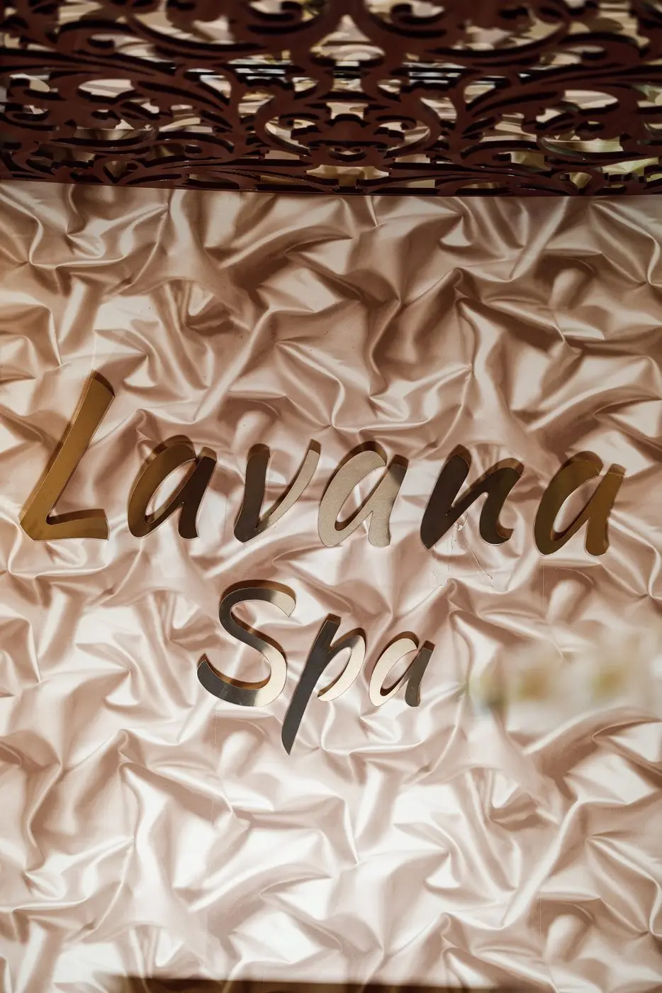 The Lavana Spa name in gold lettering on the pleated wall behind reception at Al Barsha