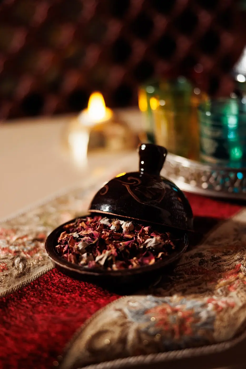 Bowl of dried rose petals and argan oils set out on the bench beside the hammam room