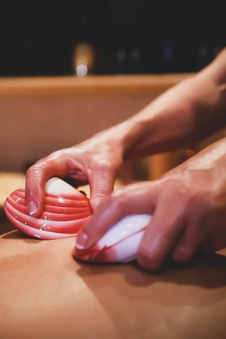 Close-up of a heated lava shell being worked along the back at Lavana Spa