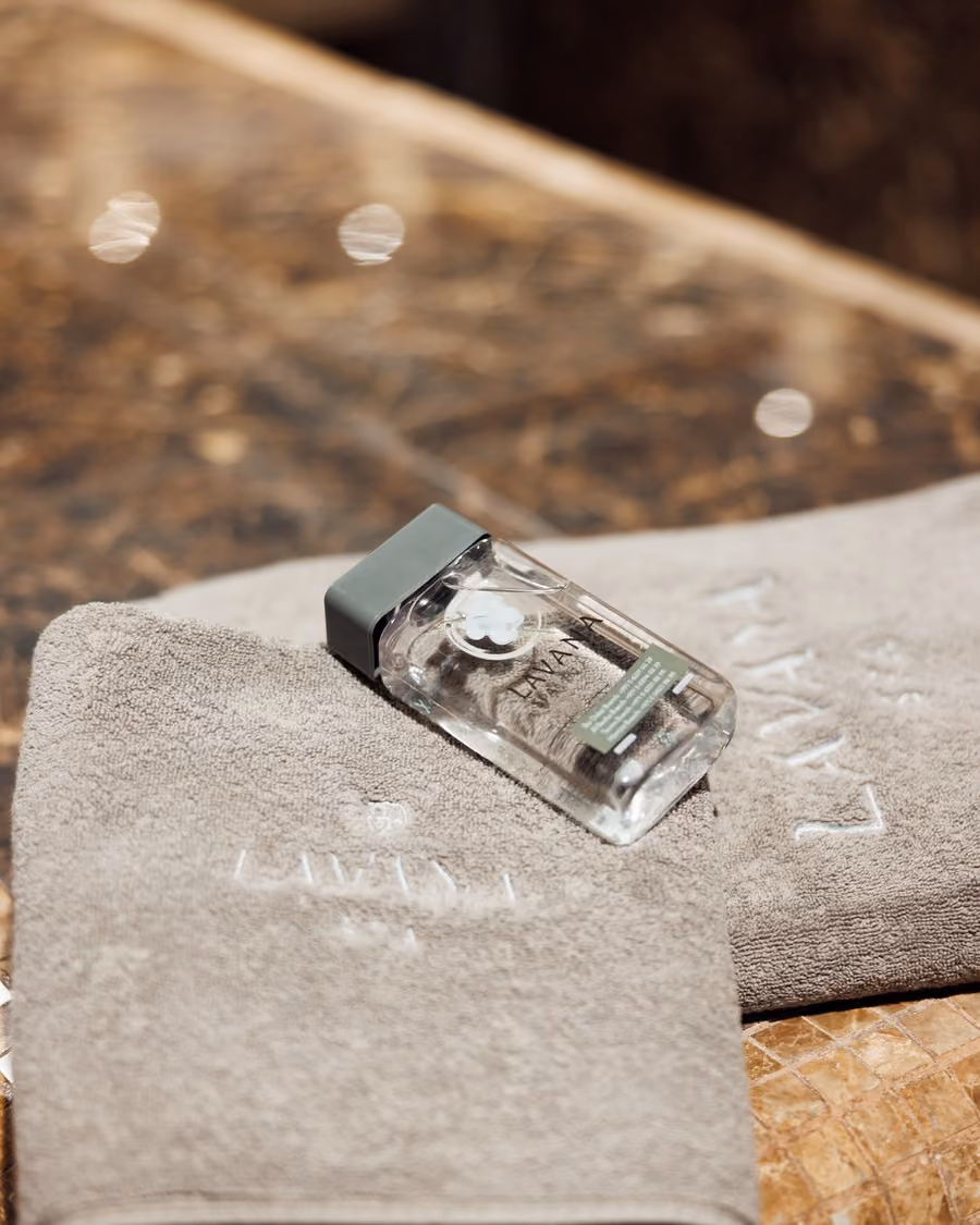 A Lavana Spa bottle resting on folded towels on the marble bench of the hammam