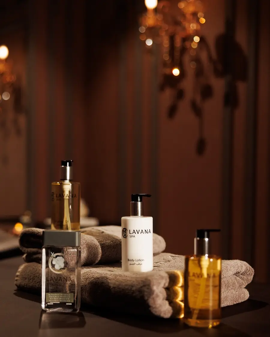 Lavana Spa body lotion, oils and rolled towels under a chandelier at Lavana Spa Bur Dubai